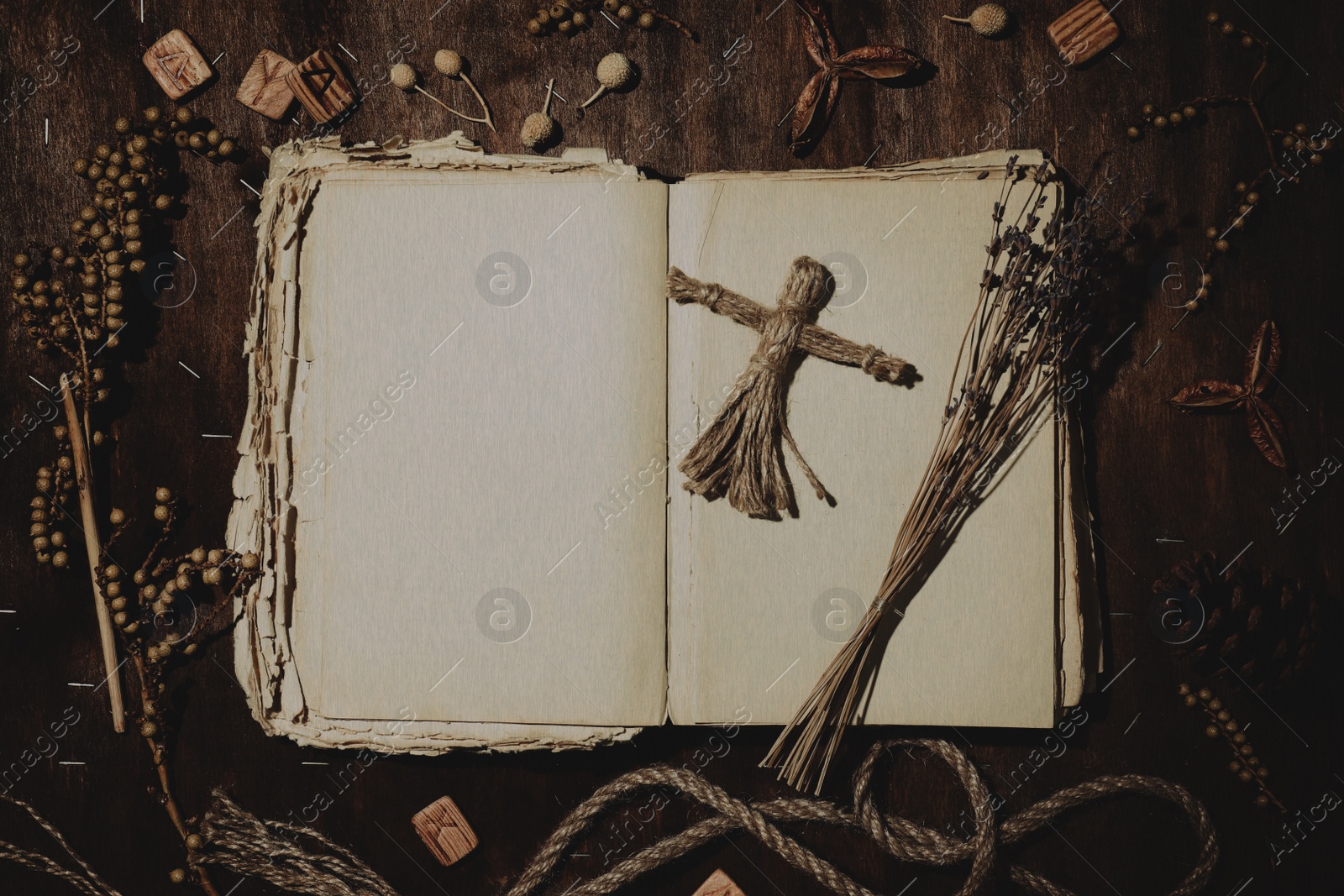 Image of Voodoo doll with pins surrounded by ceremonial items on wooden background, flat lay