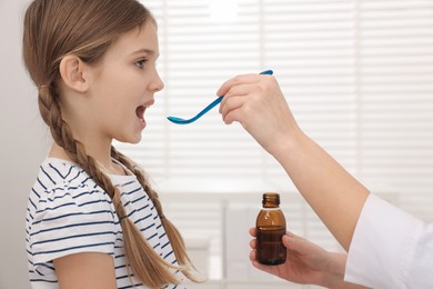Photo of Doctor giving cough syrup to girl in clinic