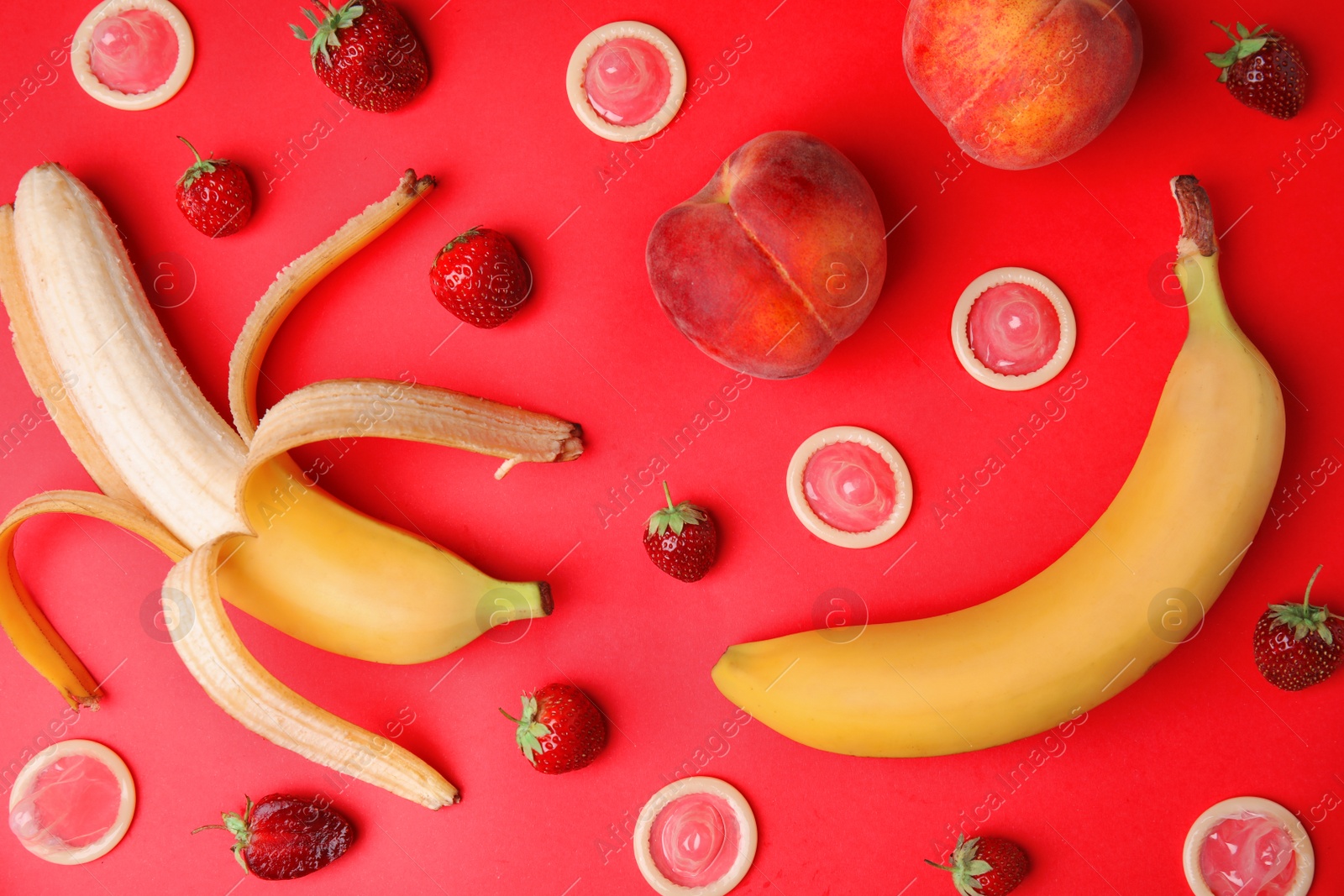 Photo of Flat lay composition with condoms and exotic fruits on red background. Erotic concept