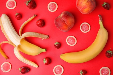 Photo of Flat lay composition with condoms and exotic fruits on red background. Erotic concept