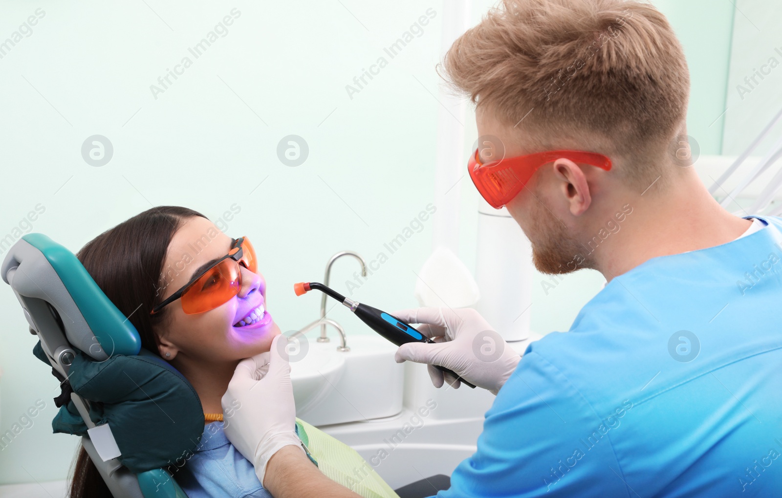 Photo of Professional dentist working with patient in modern clinic. Teeth whitening