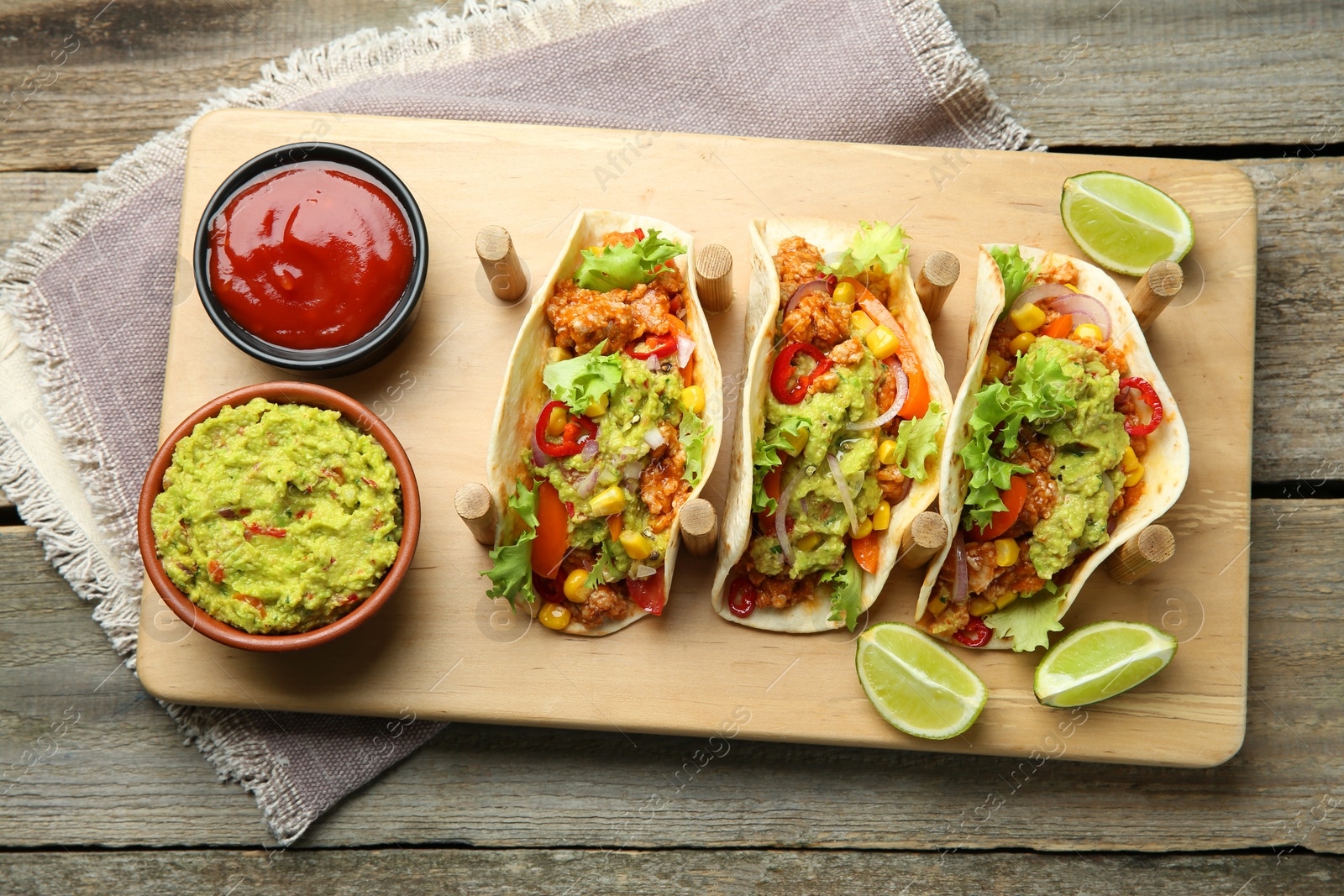 Photo of Delicious tacos with guacamole, meat and vegetables served on wooden table, top view