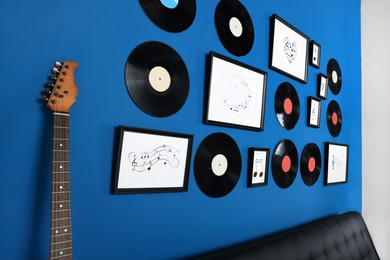 Photo of Vinyl records and different pictures on blue wall in living room