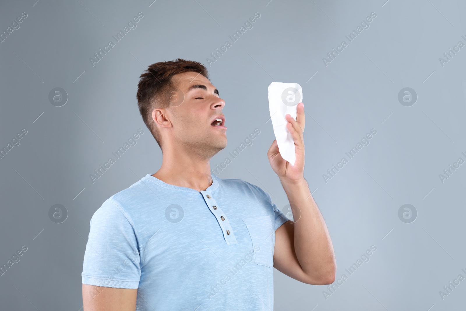 Photo of Young man suffering from allergy on grey background