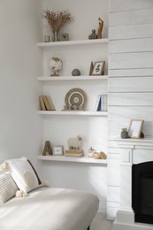 Photo of Many shelves with different decor near sofa in room. Interior design