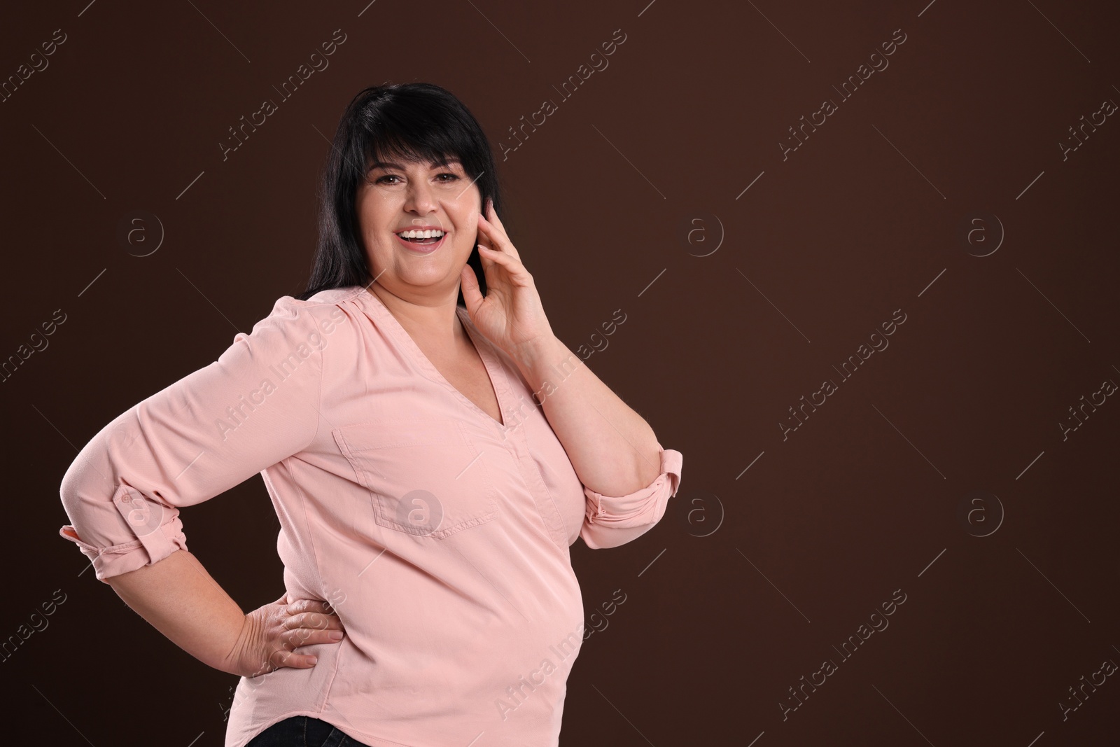 Photo of Beautiful overweight mature woman with charming smile on brown background. Space for text