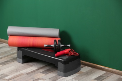 Photo of Set of fitness equipment on floor near color wall. Space for text