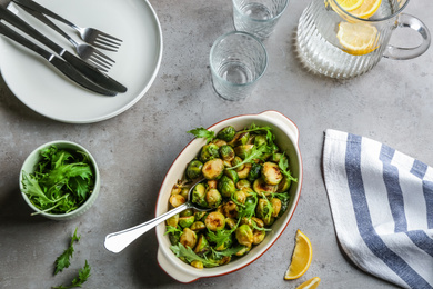 Roasted Brussels sprouts and water with lemon served on grey table, flat lay