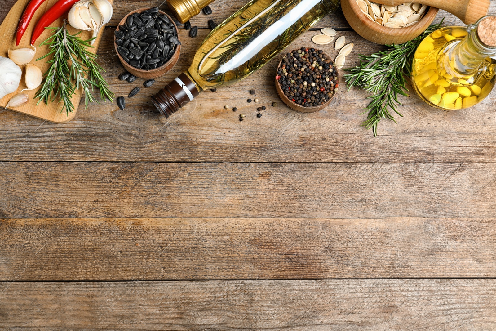 Photo of Different cooking oils on wooden table, flat lay. Space for text