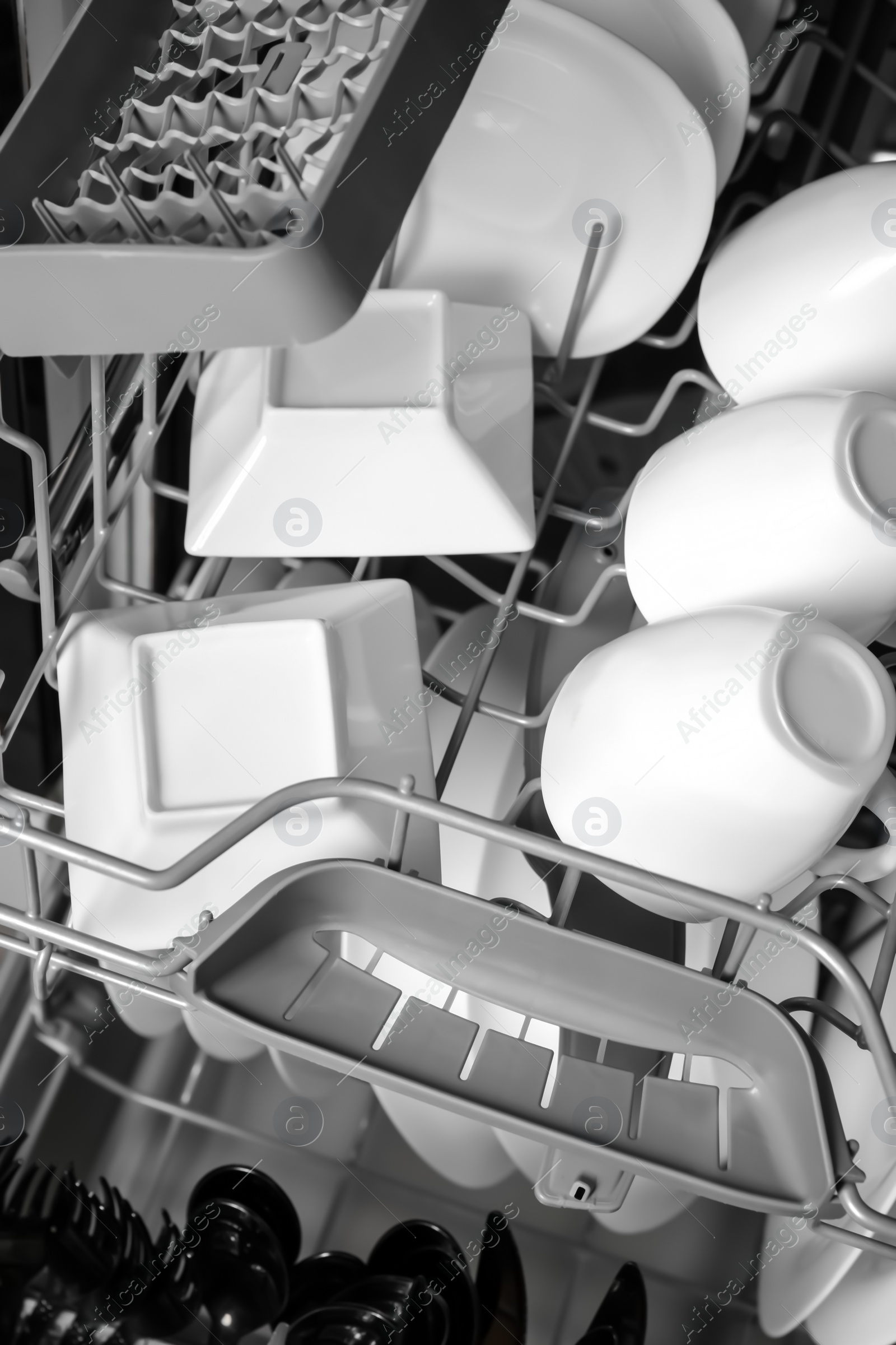 Photo of Open modern dishwasher with clean tableware, closeup