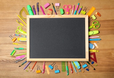 Photo of Flat lay composition with different school stationery and small chalkboard on wooden background