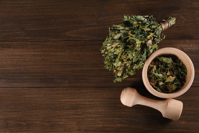 Photo of Mortar and pestle with dry parsley on wooden table, flat lay. Space for text