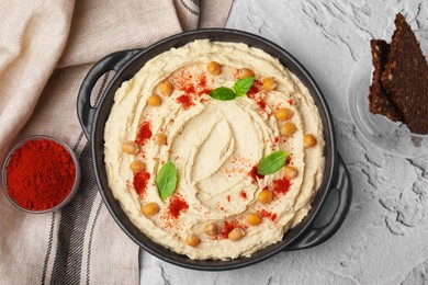 Photo of Delicious hummus with chickpeas and paprika served on white textured table, flat lay