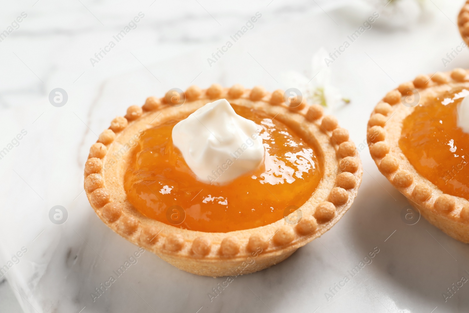 Photo of Tasty tartlets with jam on light background, closeup