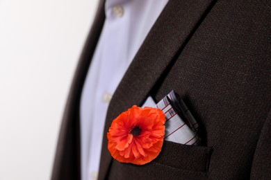 Man with with red poppy flower in suit pocket, closeup view. Remembrance symbol