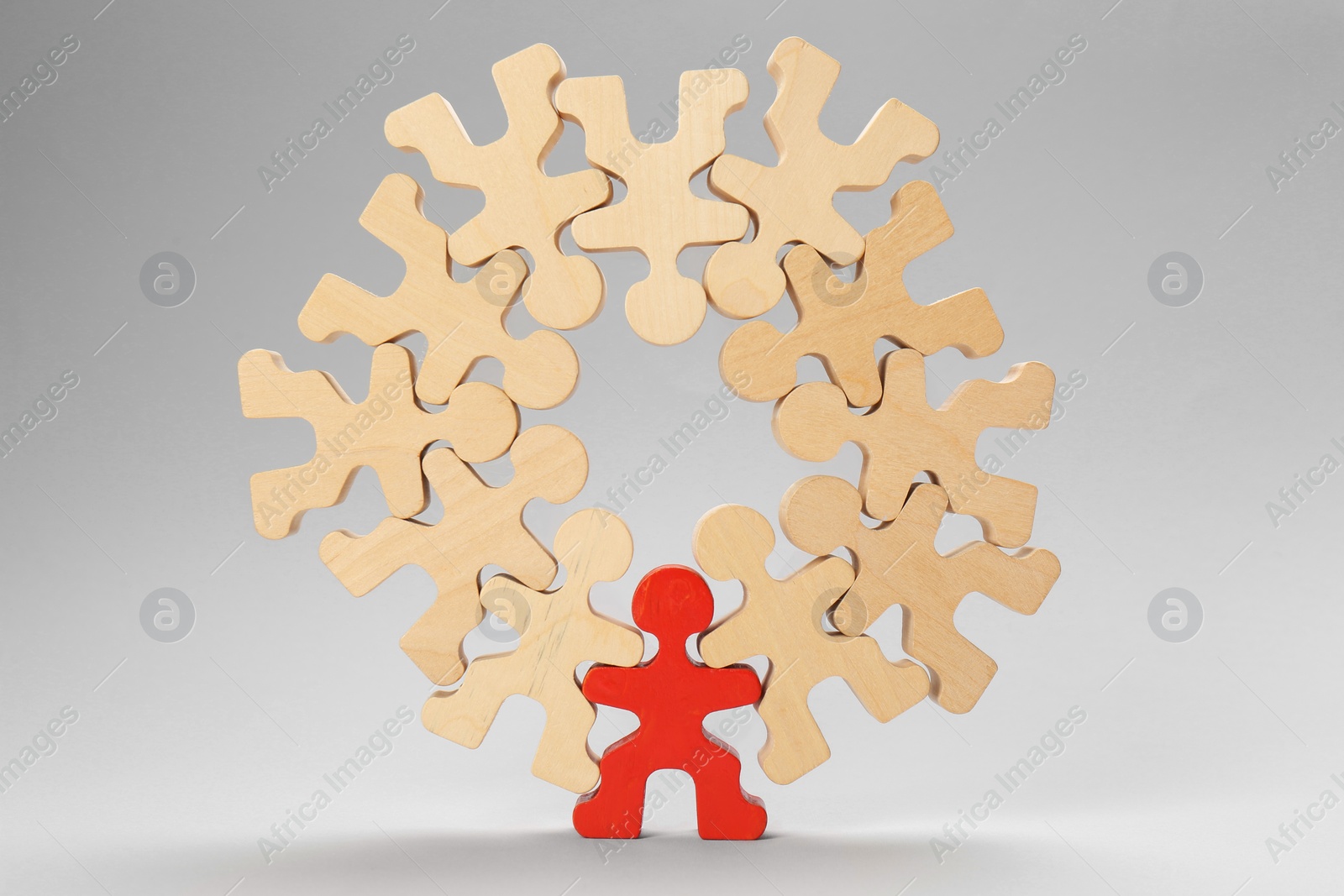 Photo of Recruitment and team work concept. Red human figure among wooden ones on light grey background