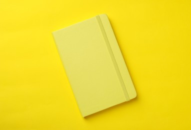 Photo of New stylish planner with hard cover on yellow background, top view