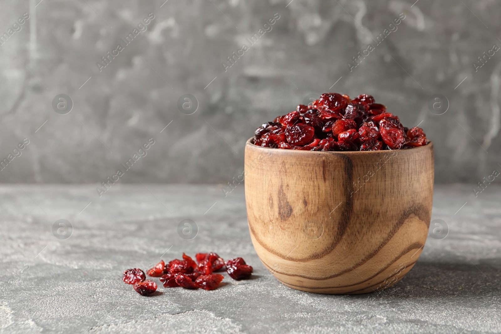 Photo of Bowl of sweet cranberries on table, space for text. Dried fruit as healthy snack