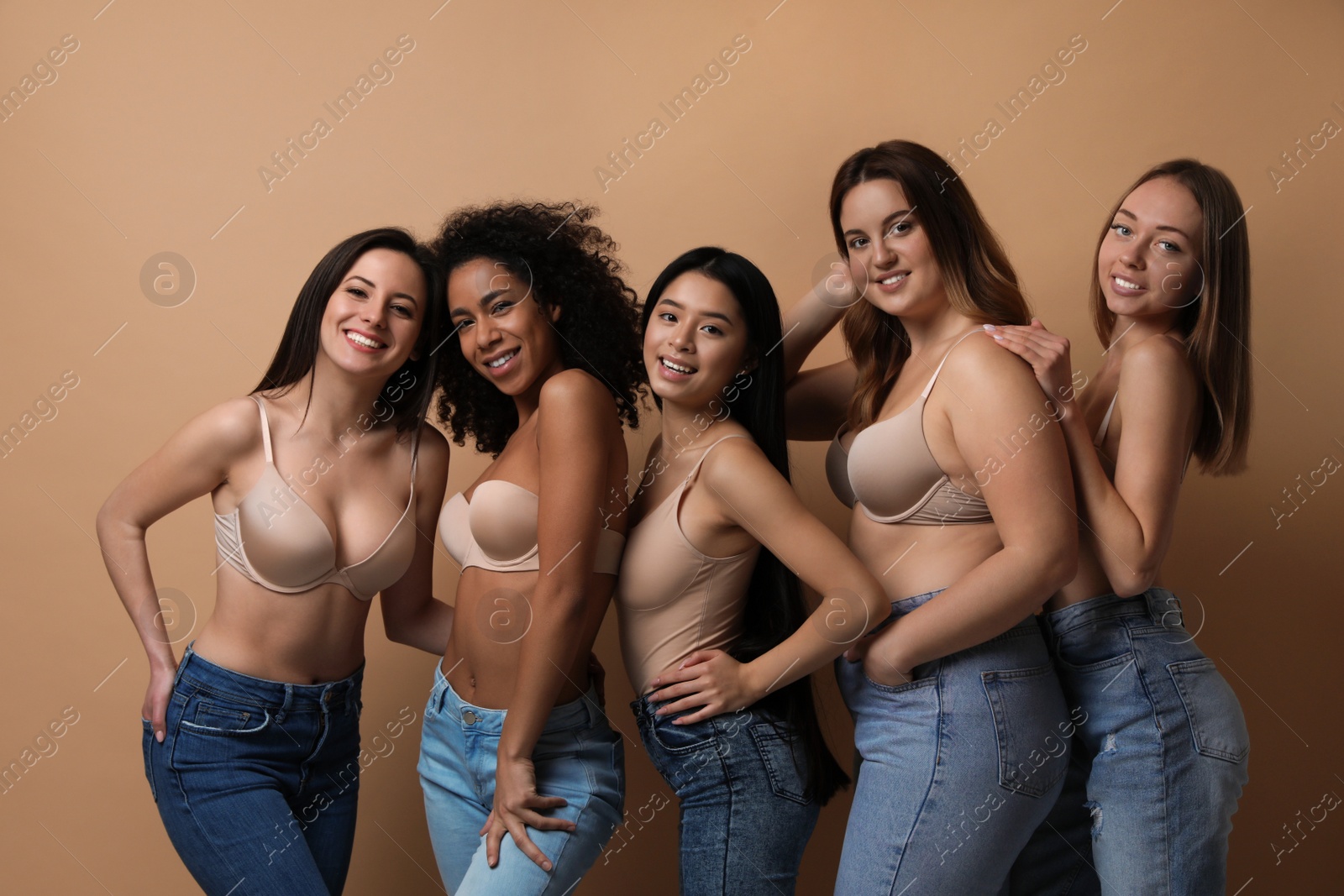 Photo of Group of women with different body types in jeans and underwear on beige background