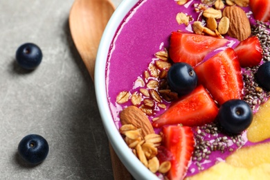 Photo of Delicious acai smoothie with granola and berries in bowl on table, closeup