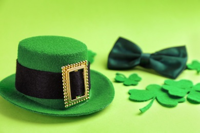 Photo of Leprechaun's hat and decorative clover leaves on green background. St. Patrick's day celebration