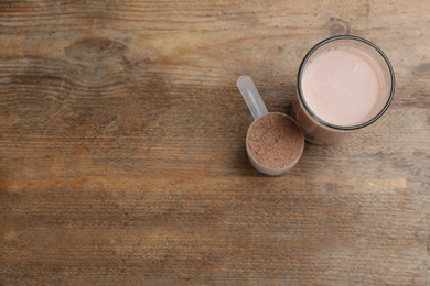 Protein shake and powder on wooden table, flat lay. Space for text