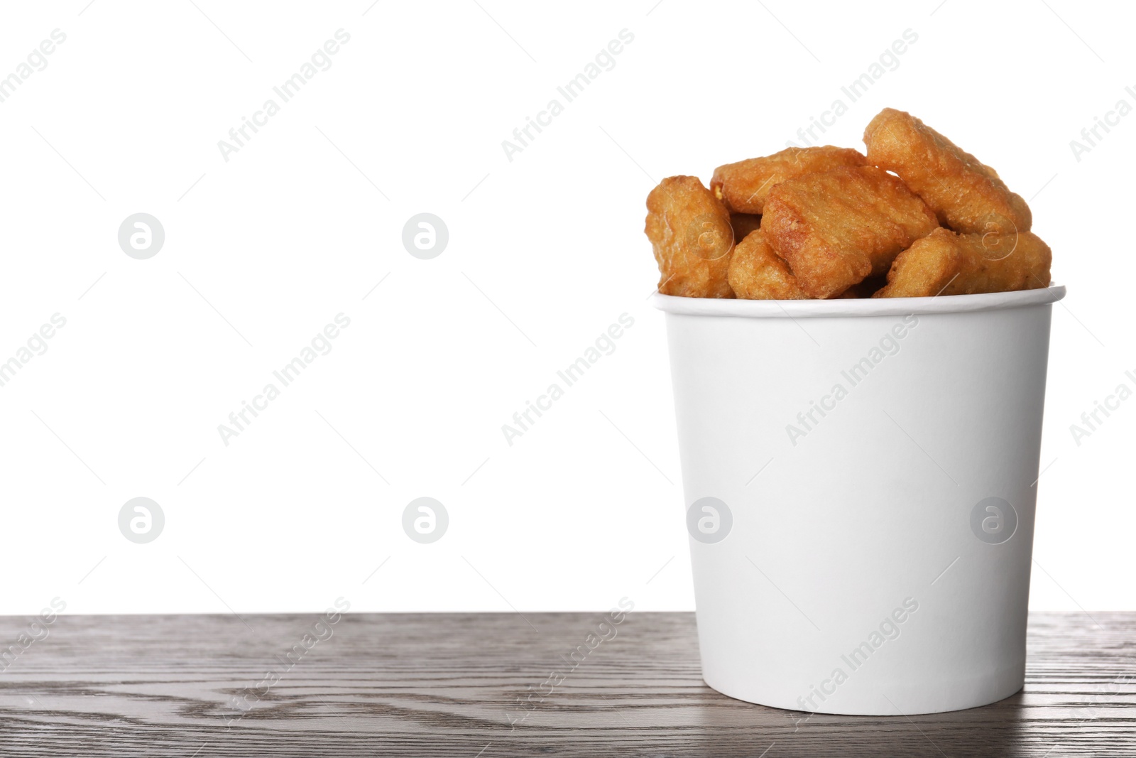 Photo of Bucket with tasty chicken nuggets on wooden table against white background. Space for text