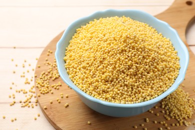 Photo of Millet groats in bowl on light wooden table