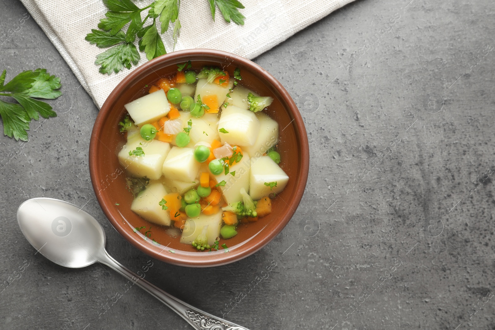 Photo of Bowl of fresh homemade vegetable soup served on grey table, flat lay. Space for text