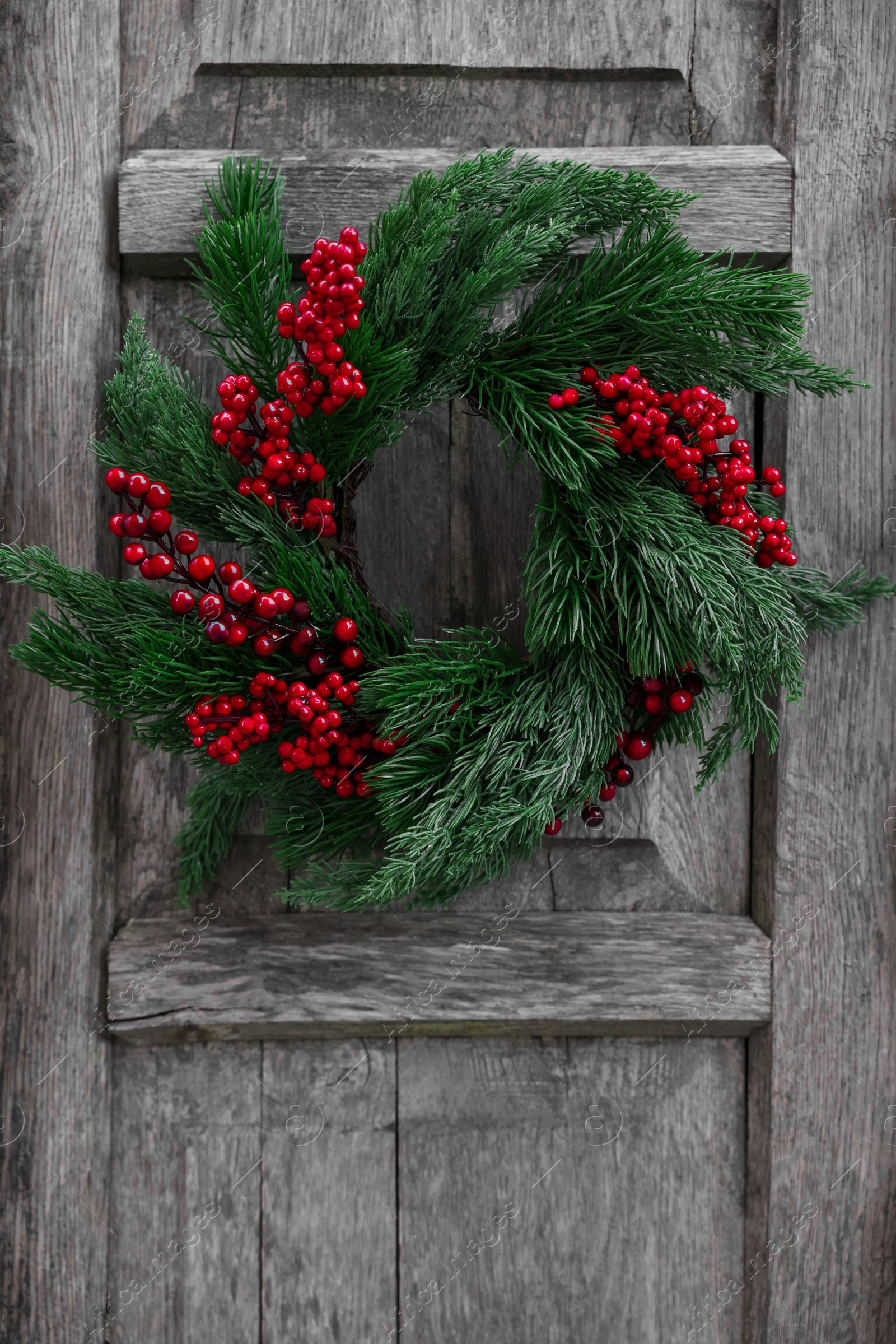 Photo of Beautiful Christmas wreath with red berries hanging on wooden wall