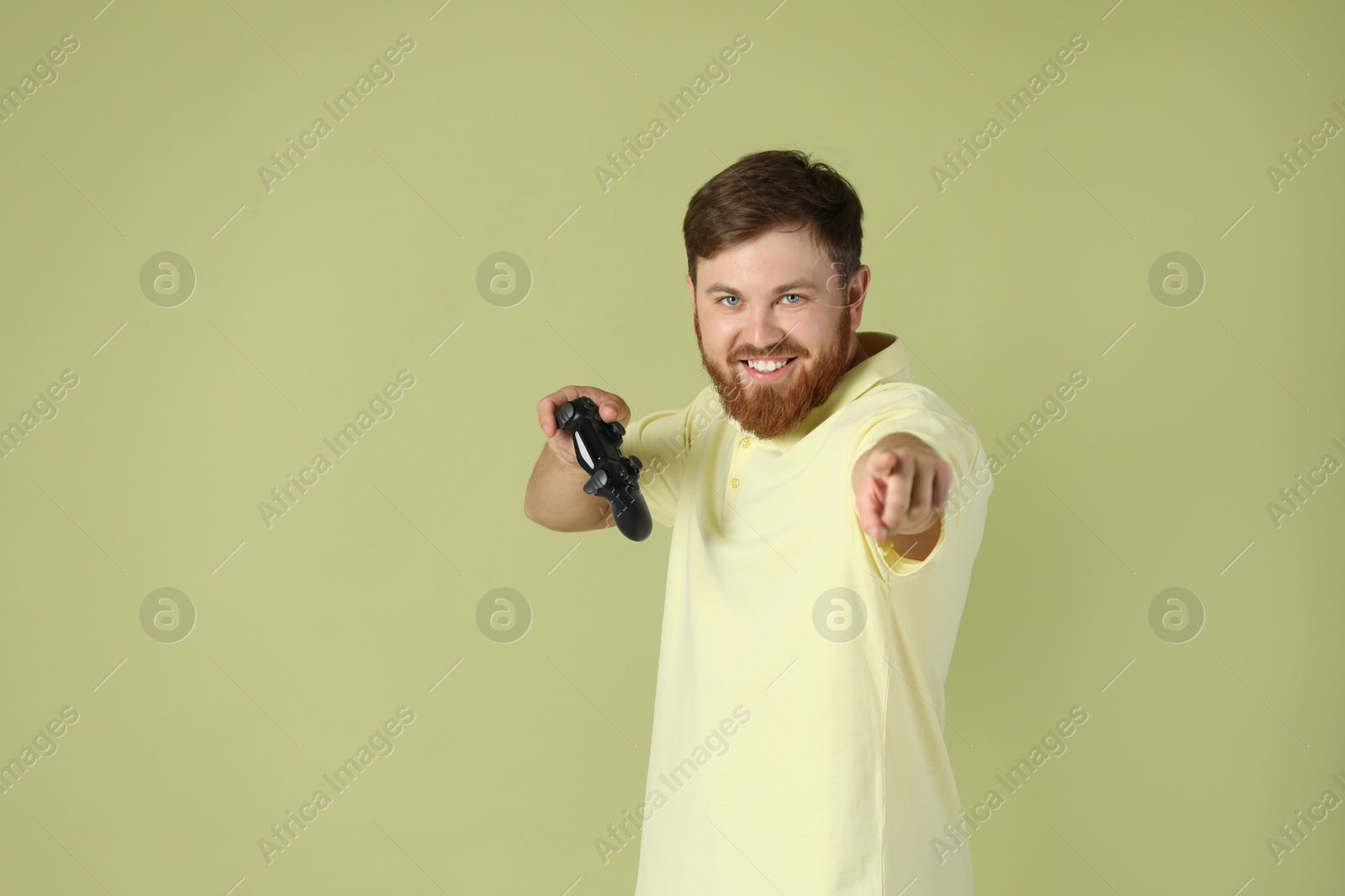 Photo of Happy man with game controller on pale green background. Space for text