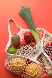 String bag with different vegetables and fruits on red background, top view