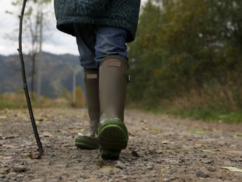 Photo of Woman in rubber boots walking outdoors, closeup