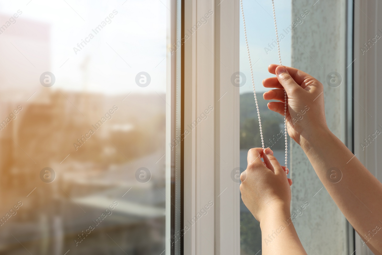 Photo of Woman opening blinds on window indoors, closeup. Space for text
