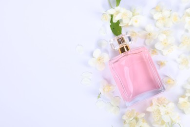 Photo of Aromatic perfume in bottle and beautiful jasmine flowers on white background, flat lay. Space for text