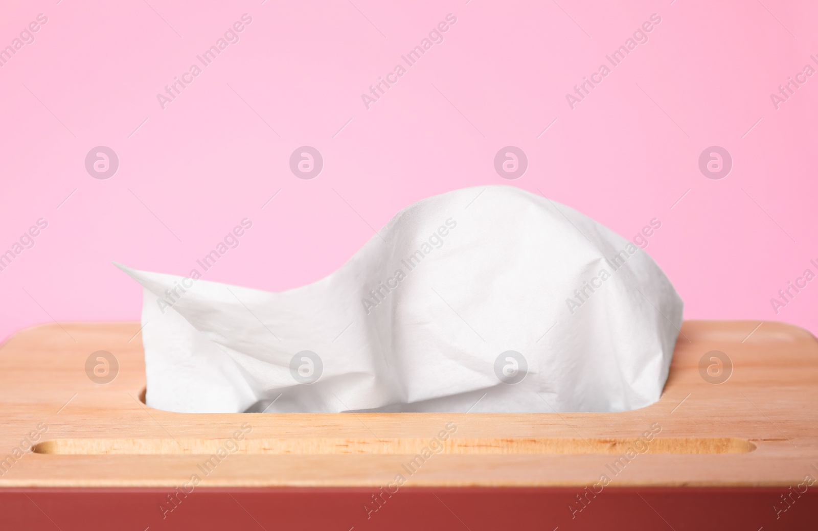 Photo of Holder with paper tissues on pink background, closeup