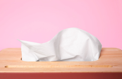 Photo of Holder with paper tissues on pink background, closeup