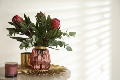 Vase with bouquet of beautiful Protea flowers on table indoors