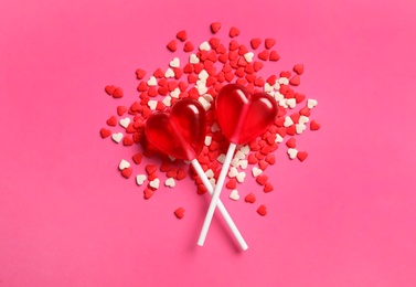 Photo of Sweet heart shaped lollipops and sprinkles on pink background, flat lay. Valentine's day celebration