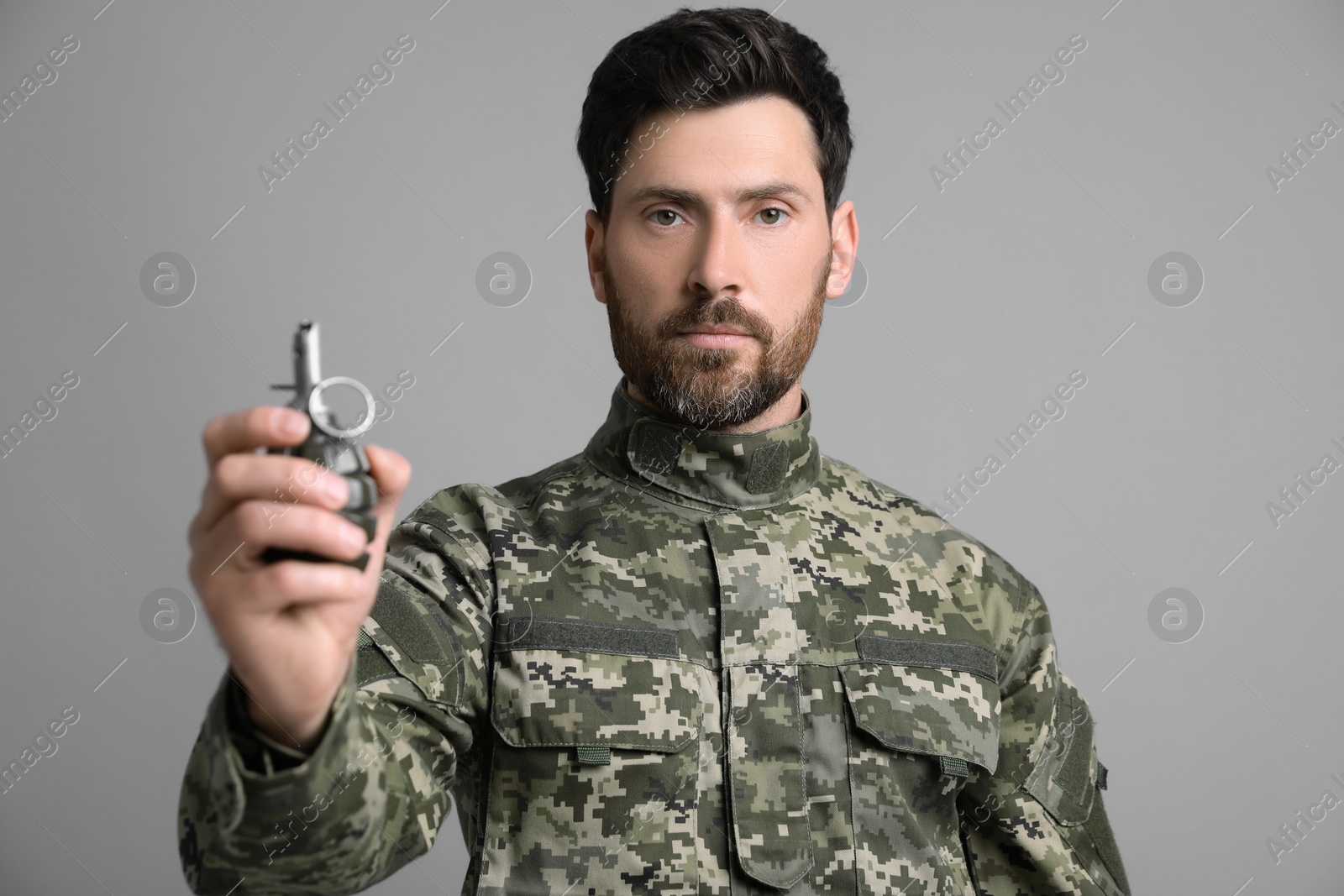 Photo of Soldier holding hand grenade on light grey background. Military service