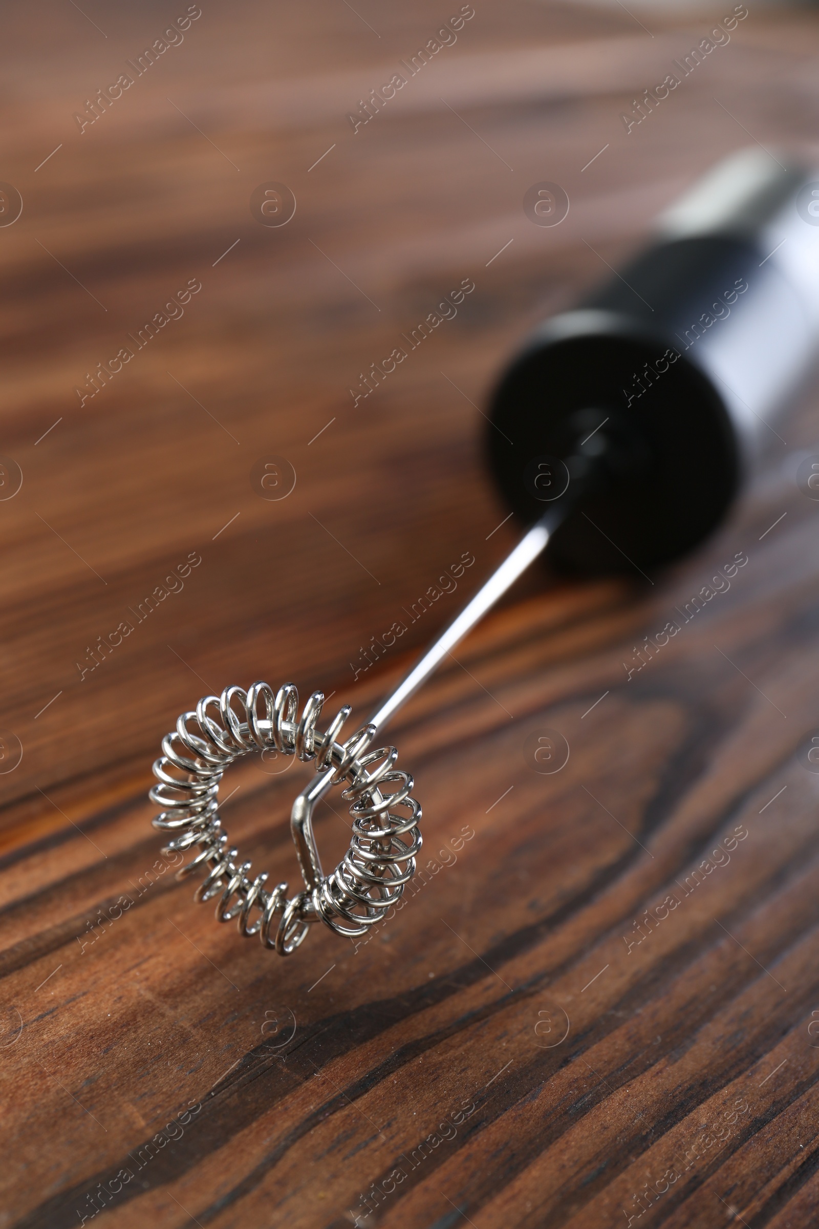 Photo of Black milk frother wand on wooden table, closeup