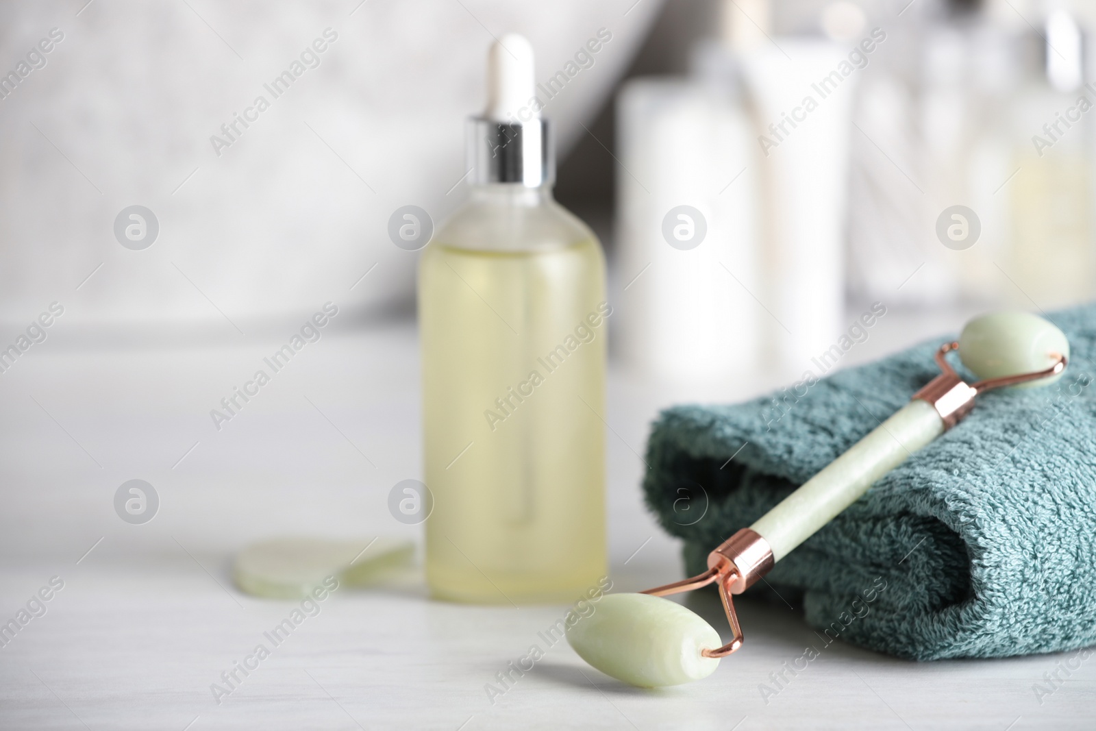 Photo of Natural face roller, gua sha tool and serum on white table, closeup. Space for text