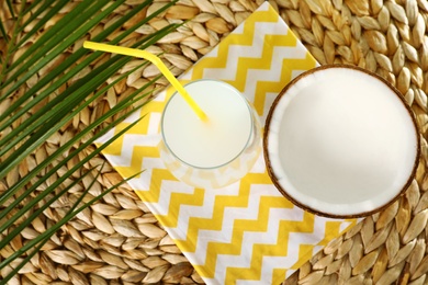 Flat lay composition with glass of coconut water on wicker background