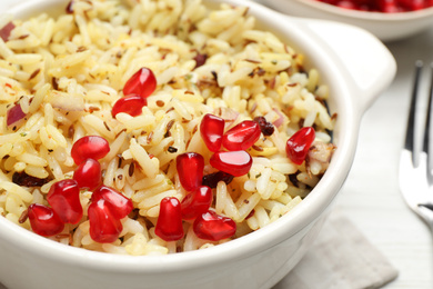 Photo of Tasty rice pilaf with pomegranate grains on table, closeup