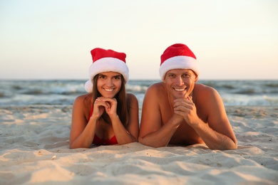 Happy couple with Santa hats together on beach. Christmas vacation