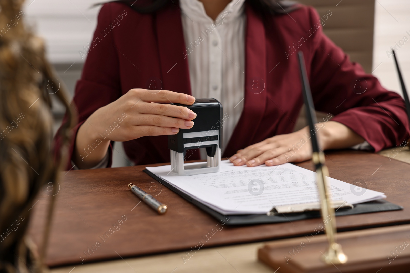 Photo of Notary stamping document at table in office, closeup