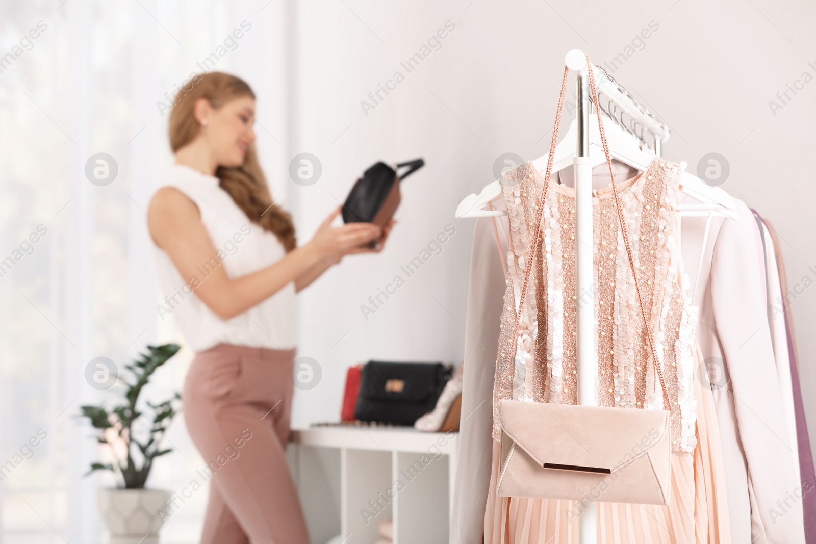 Photo of Rack with stylish clothes and woman on background. Space for text