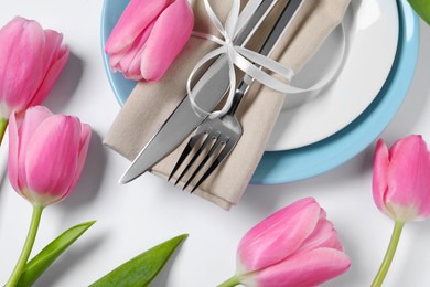 Photo of Stylish table setting with cutlery and tulips on white background, flat lay