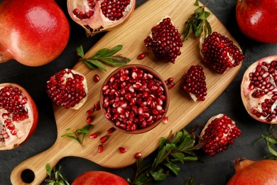 Photo of Delicious ripe pomegranates on black table, flat lay