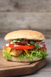 Photo of Delicious burger with tofu and fresh vegetables on wooden table